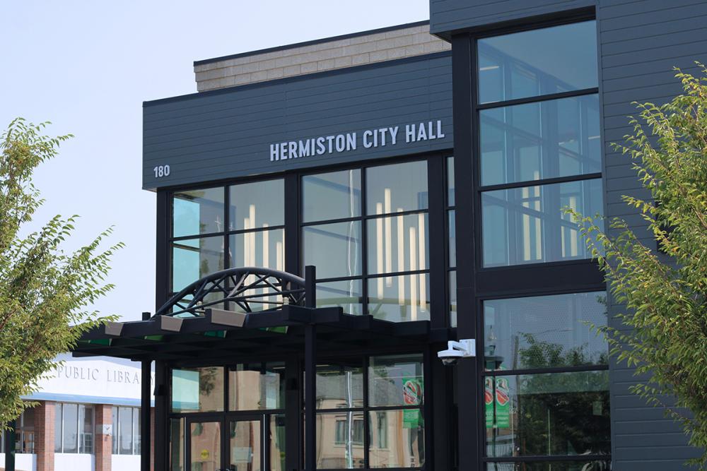 The front entrance of Hermiston City Hall with two trees in the foreground.