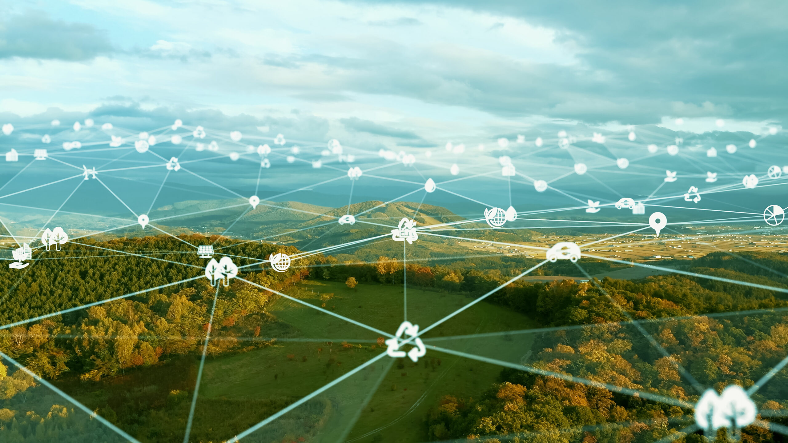 A photo illustration of netowk nodes connected by lines overlaying an aerial photo of a rural landscape.