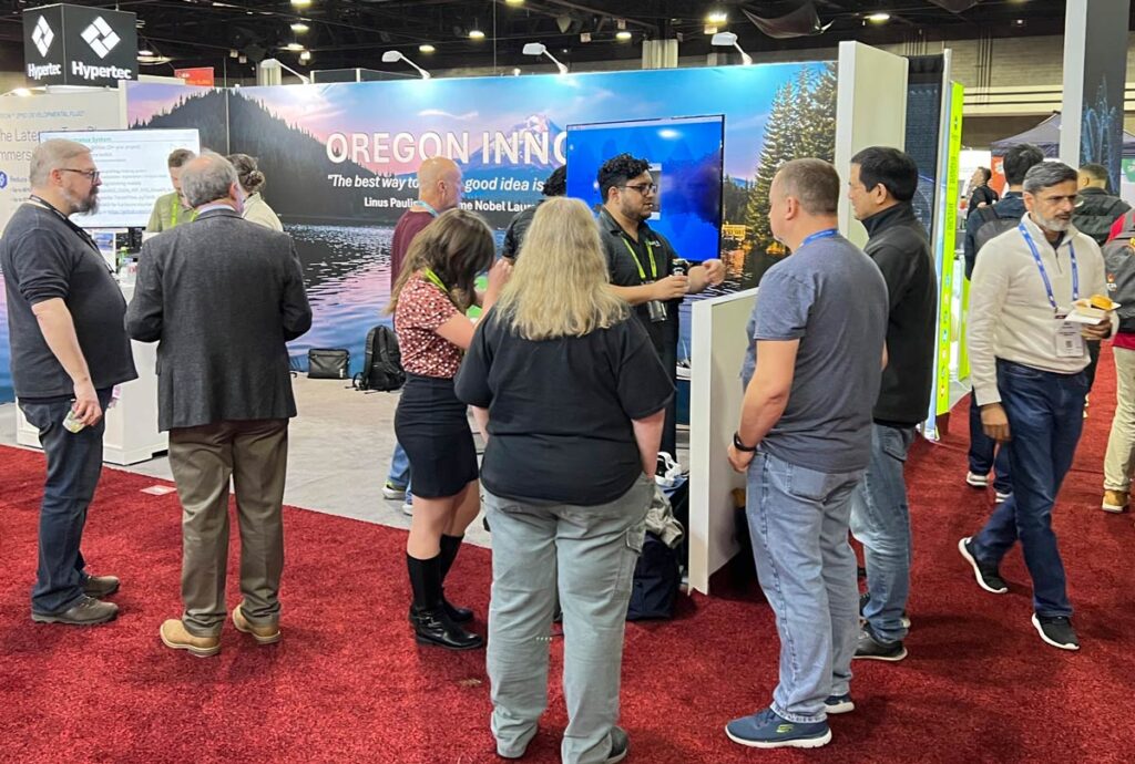 Multiple people standing in front of Link Oregon's booth at the Supercomputing 2024 convention.